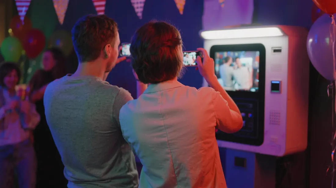 Des clients se prennent en photo devant la borne YourPhotoBox